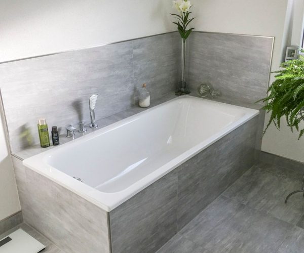 gemauerte Eckbadewanne mit grauen Fliesen